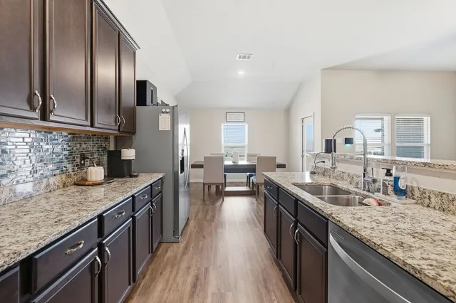 a kitchen with stainless steel appliances granite countertop a sink a stove and a wooden floors
