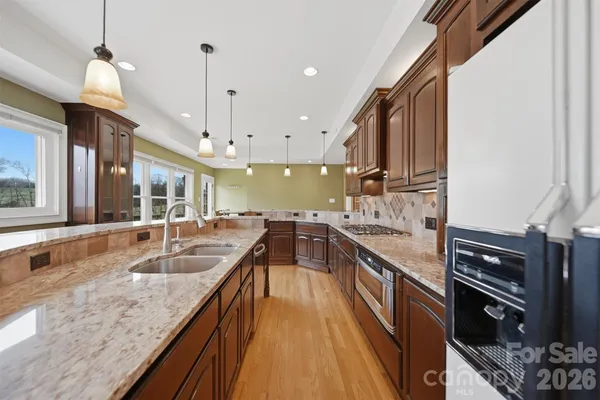 a kitchen with stainless steel appliances granite countertop a sink a stove and a wooden floors