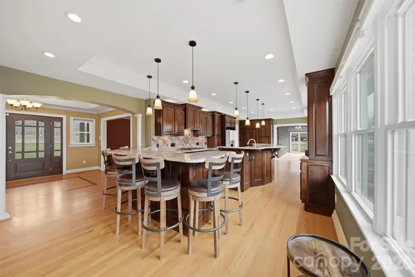 a dining room with stainless steel appliances kitchen island granite countertop a table chairs and a refrigerator