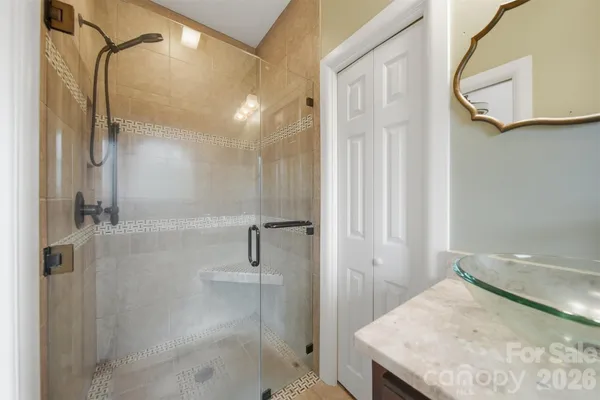 a bathroom with a granite countertop sink a mirror and shower