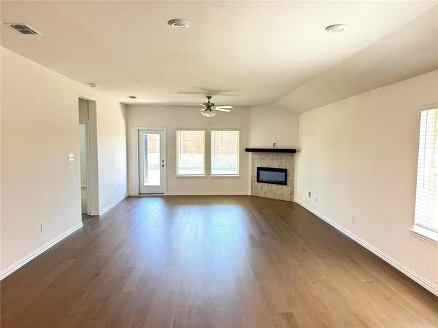 an empty room with wooden floor fireplace and windows