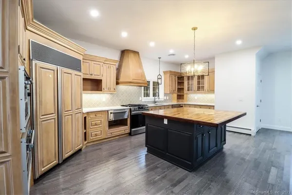 a kitchen with stainless steel appliances granite countertop a sink a stove and a wooden floor