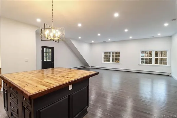 a view of a kitchen with kitchen island a sink wooden floor and a chandelier