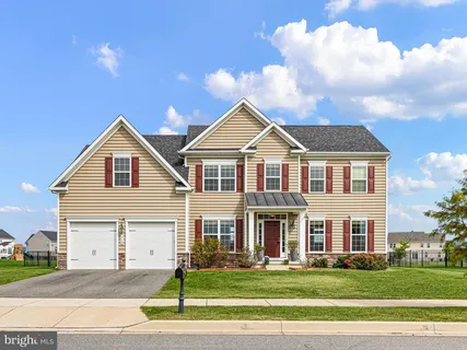 a view of a white house next to a yard with big trees