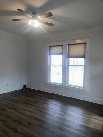 a view of an empty room with wooden floor a fireplace and a window