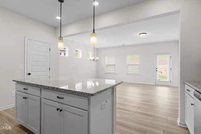 a kitchen with granite countertop a oven a white cabinets and wooden floor
