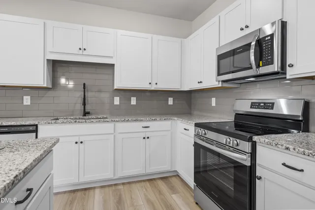 a kitchen with granite countertop white cabinets stainless steel appliances and a sink