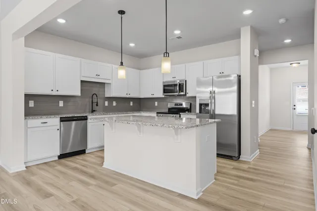 a kitchen with kitchen island white cabinets and stainless steel appliances