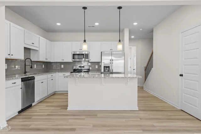 a view of kitchen with stainless steel appliances granite countertop stove top oven and cabinets