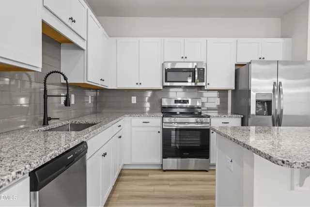 a kitchen with stainless steel appliances granite countertop a sink stove microwave and refrigerator