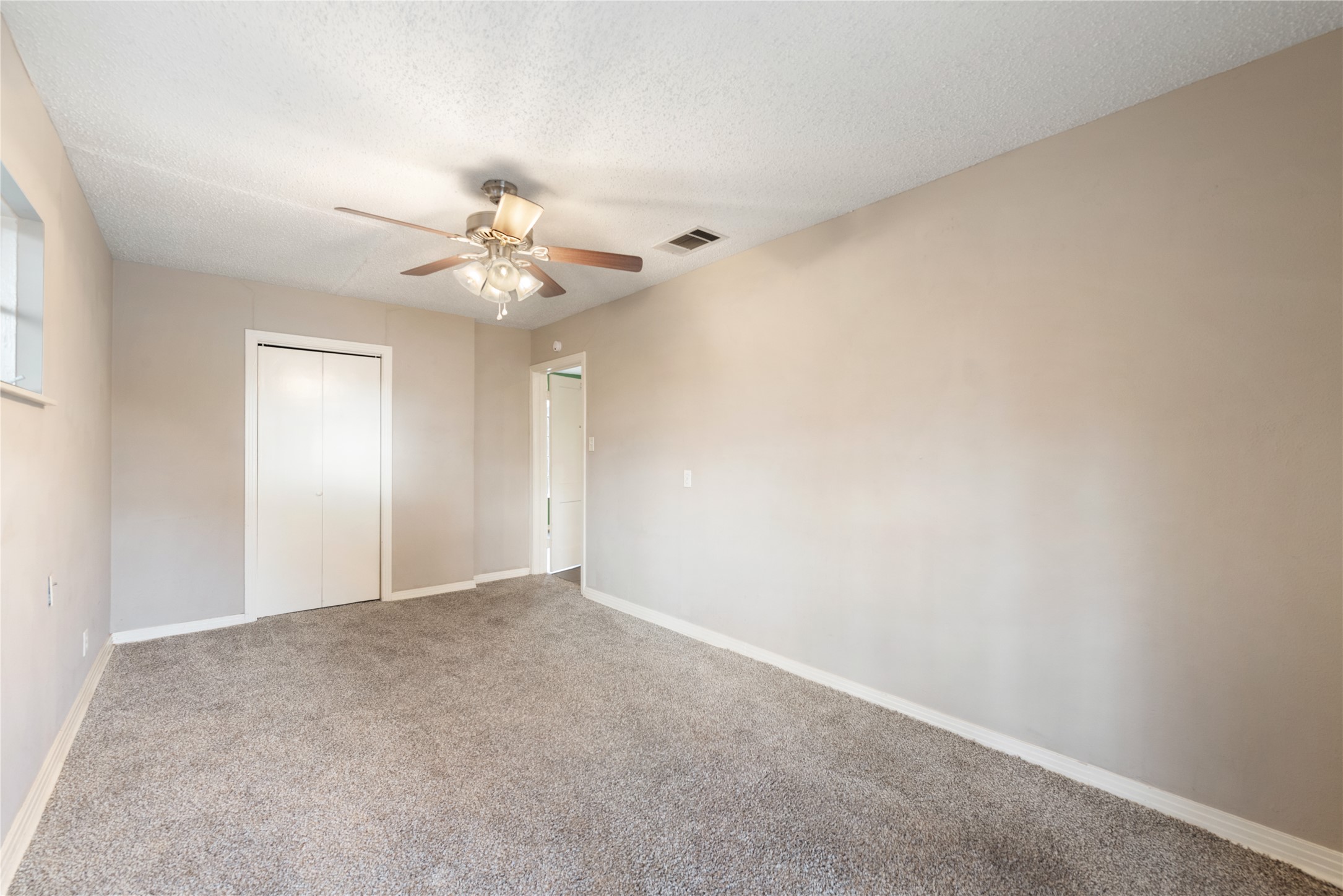 1900 Justin Lane Austin, TX 78757 - Photo 12 of 27 Unfurnished bedroom featuring carpet flooring, a closet, a textured ceiling, and ceiling fan