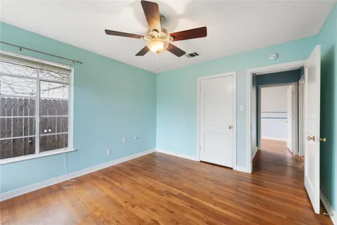 a view of empty room with wooden floor and fan