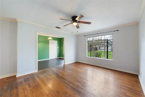 a view of empty room with wooden floor and fan