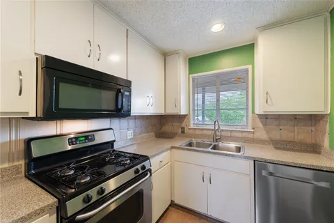 a kitchen with stainless steel appliances a stove a microwave a sink and cabinets