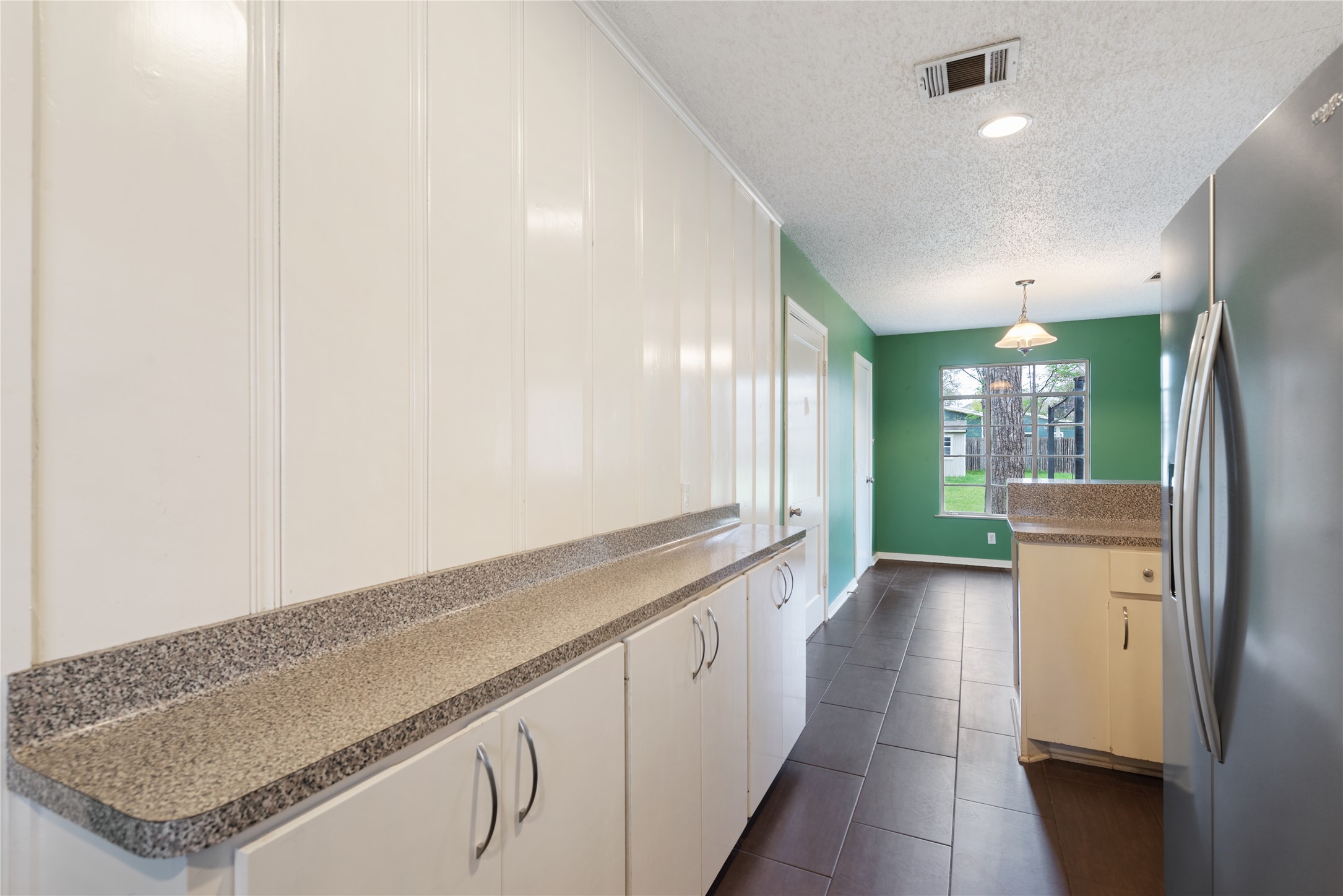 1900 Justin Lane Austin, TX 78757 - Photo 10 of 27 Kitchen featuring stainless steel fridge with ice dispenser, white cabinetry, a textured ceiling, decorative light fixtures, and dark tile patterned floors