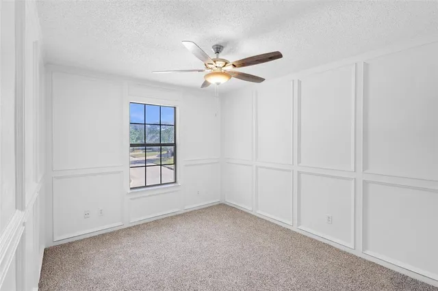 a view of an empty room with a ceiling fan and a window