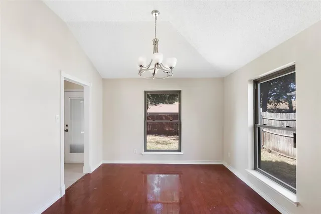 a view of a hallway with wooden floor and a chandelier
