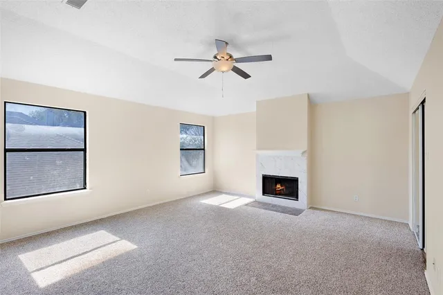 a view of a livingroom with a fireplace a ceiling fan and windows