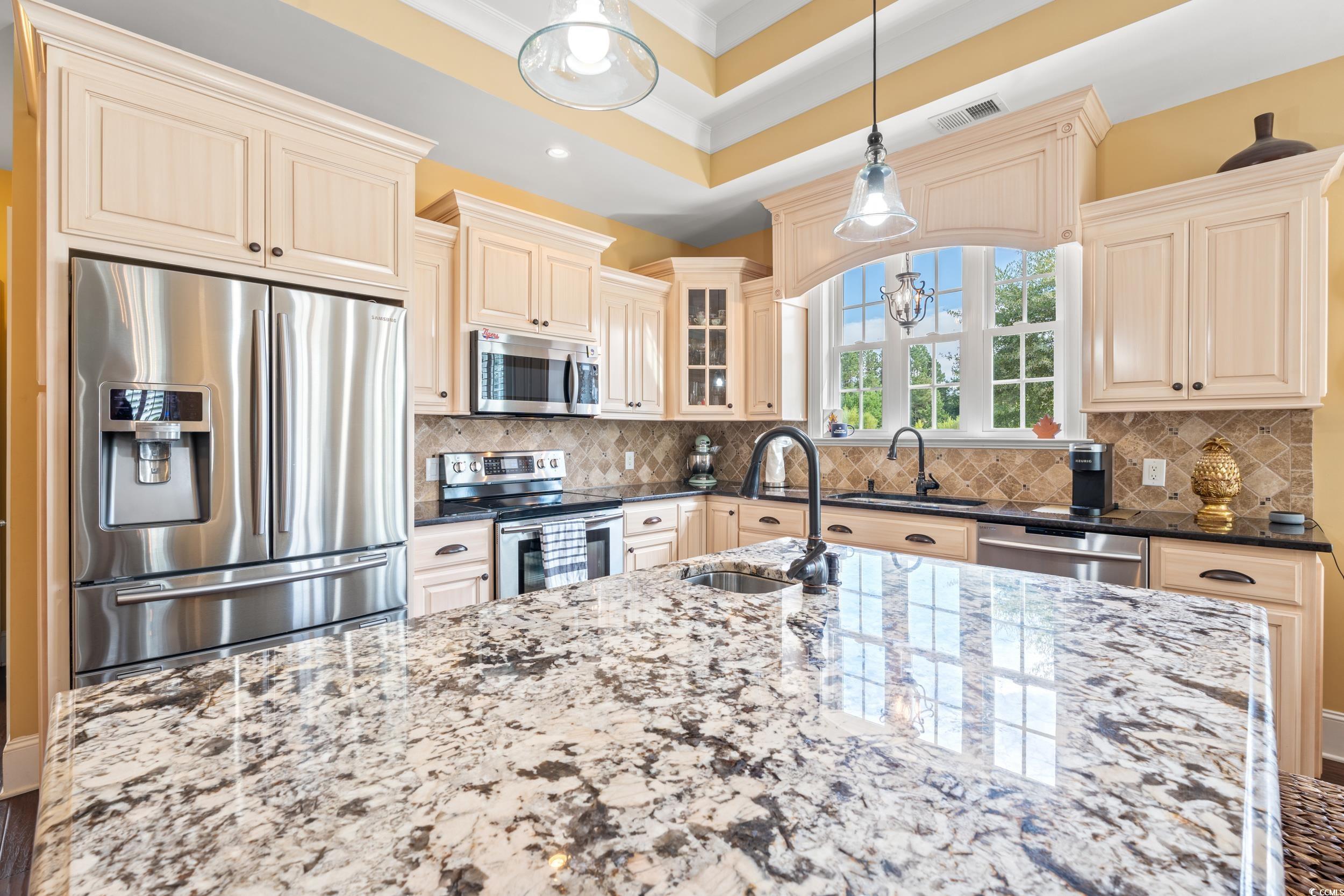 3609 Long Ave Extension Conway, SC 29526 - Photo 13 of 40 Kitchen with stainless steel appliances, dark stone counters, cream cabinetry, decorative light fixtures, and decorative backsplash