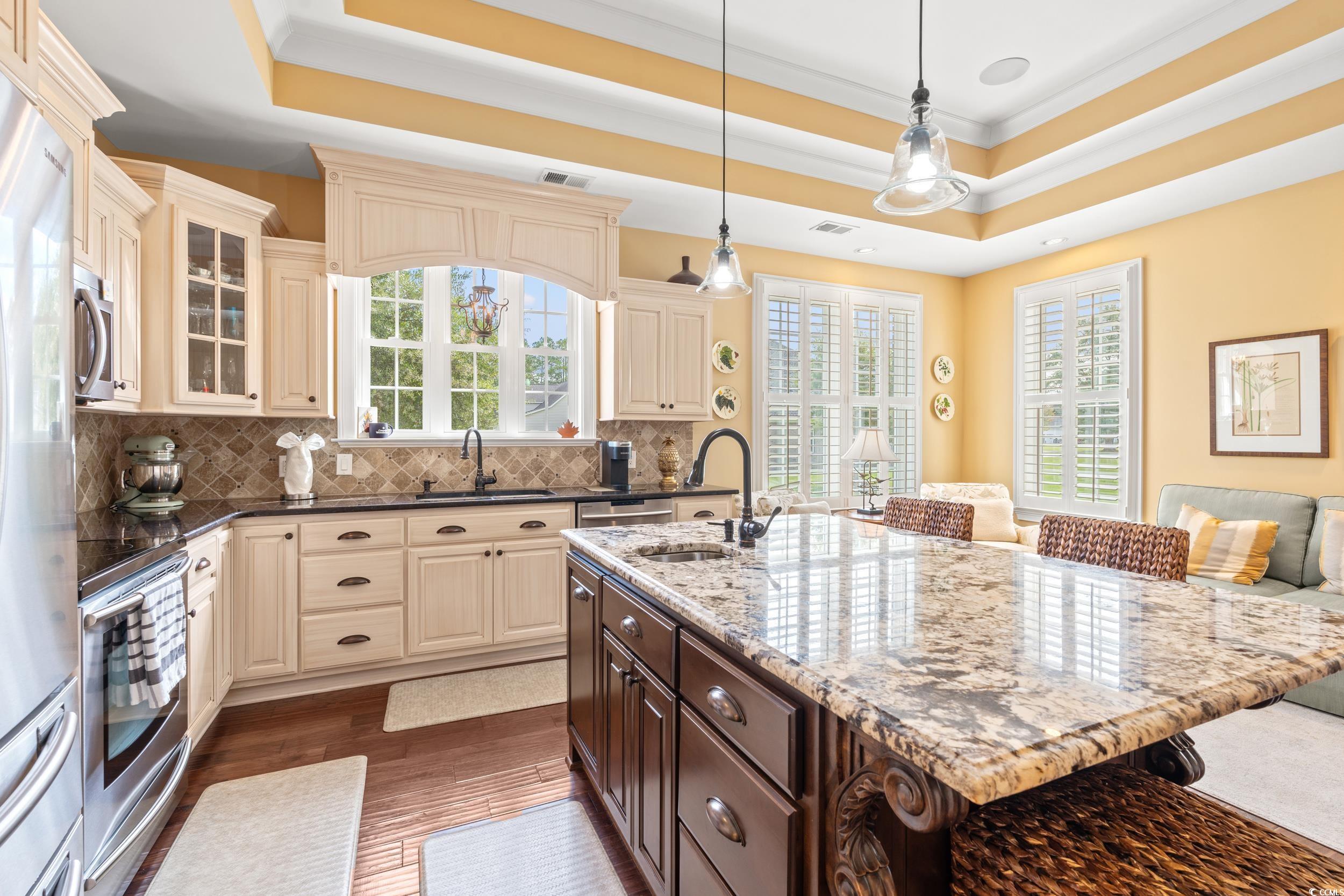 3609 Long Ave Extension Conway, SC 29526 - Photo 14 of 40 Kitchen featuring dark brown cabinets, cream cabinets, a kitchen bar, a raised ceiling, and tasteful backsplash