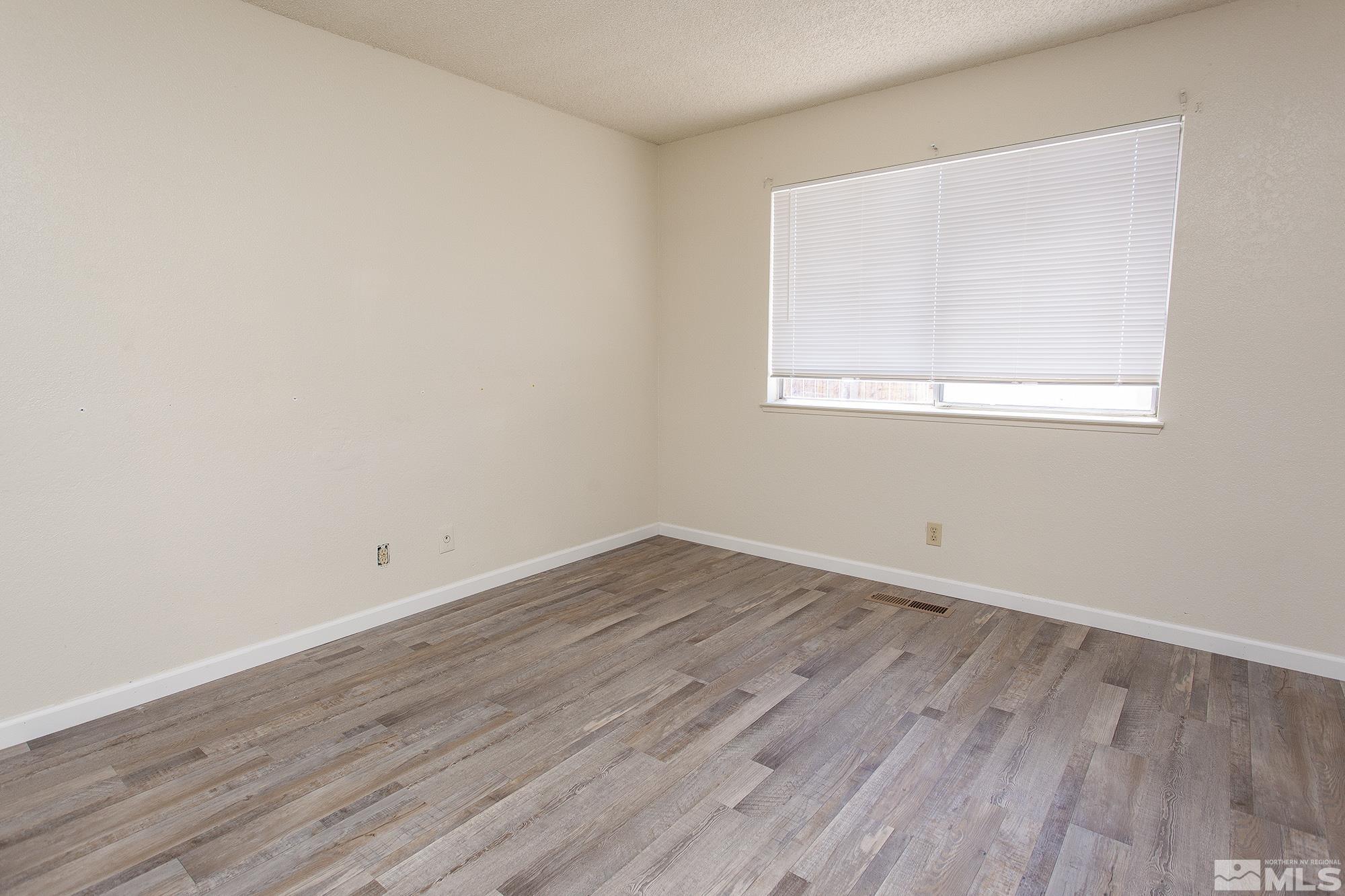 10046 Humite Lane Reno, NV 89506 - Photo 11 of 17 an empty room with wooden floor and windows