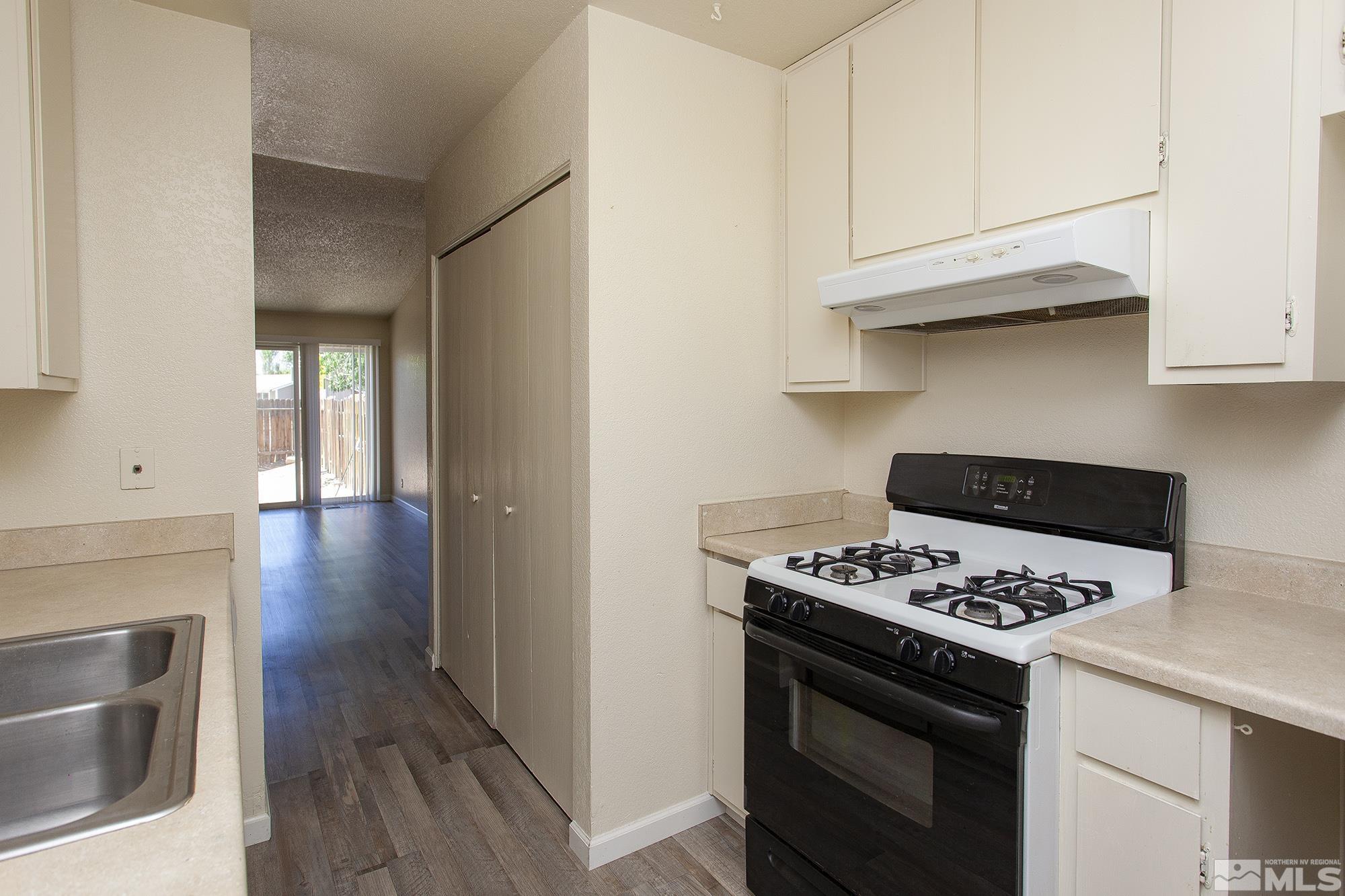 10046 Humite Lane Reno, NV 89506 - Photo 7 of 17 a kitchen with stainless steel appliances granite countertop a stove and a wooden floor