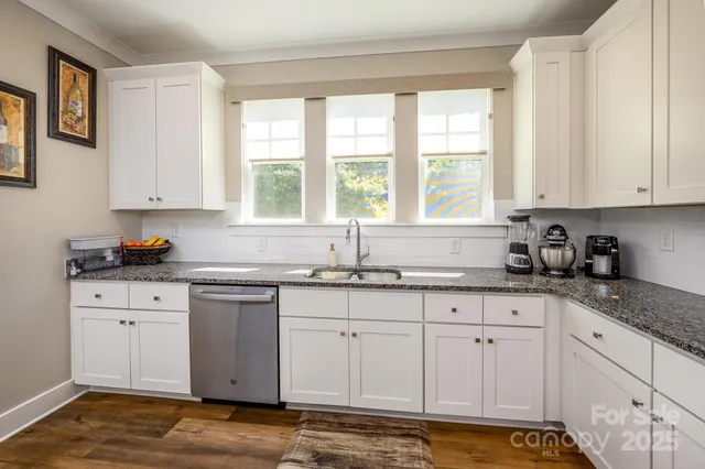 a kitchen with granite countertop white cabinets and a window