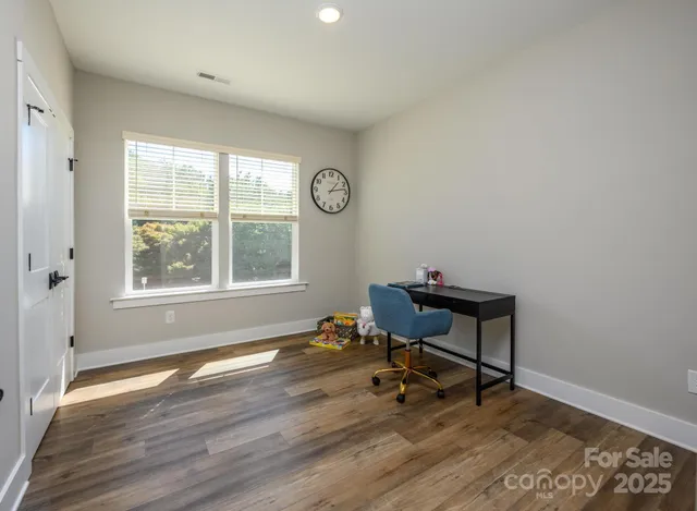 a workspace room with wooden floor and a window