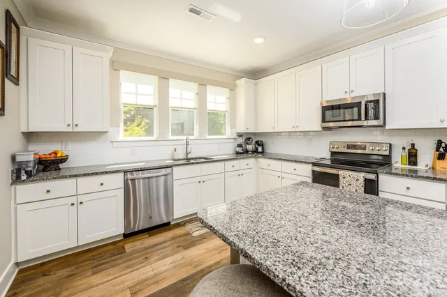 a kitchen with granite countertop a sink stainless steel appliances and cabinets