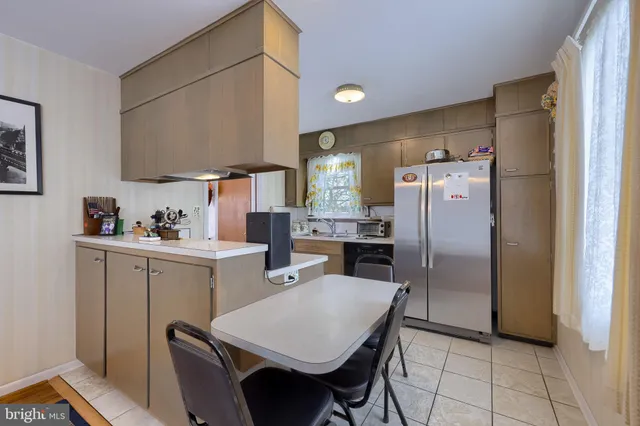 a kitchen with a refrigerator a stove a sink and a dining table with chairs