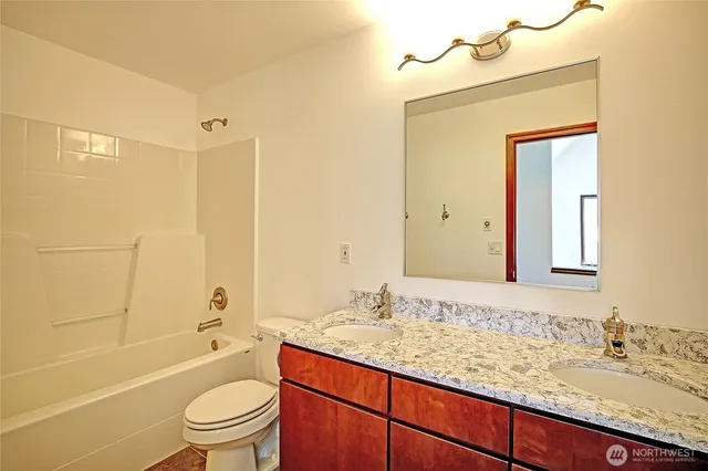 a bathroom with a granite countertop sink toilet mirror and shower