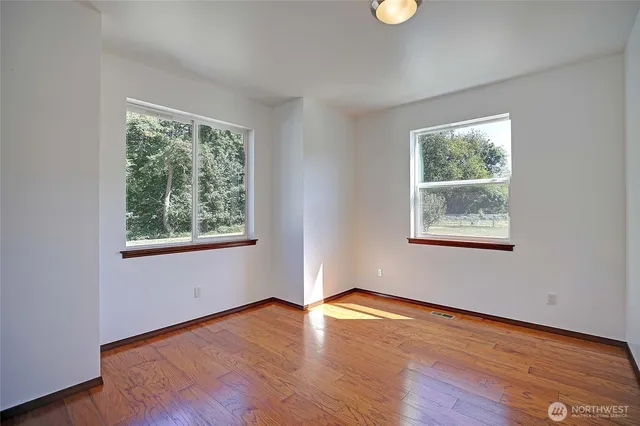a view of an empty room with wooden floor and window