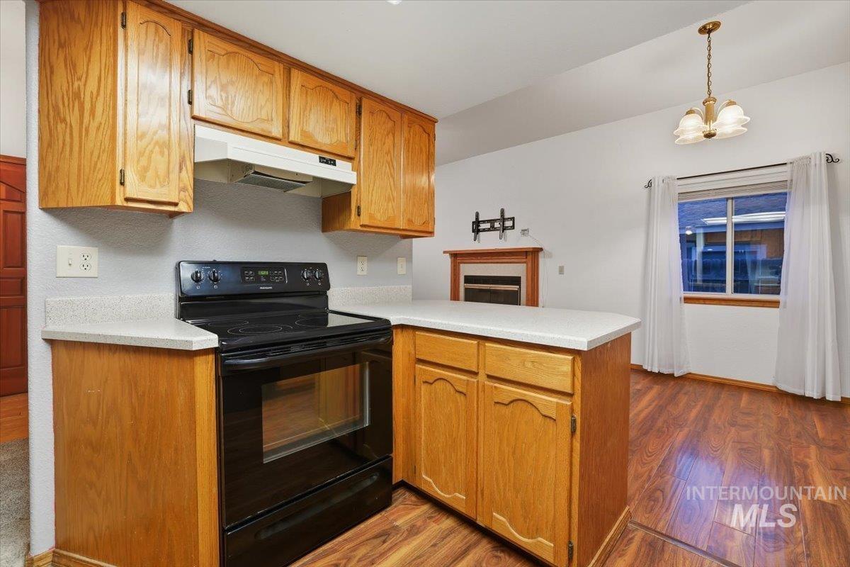 7134 West Amity Road Boise, ID 83709 - Photo 7 of 20 Kitchen featuring a peninsula, black range with electric stovetop, light wood-type flooring, light countertops, and under cabinet range hood