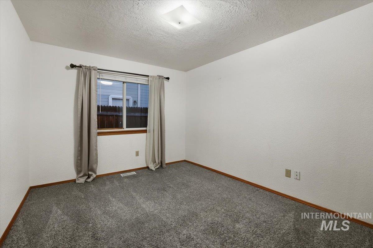7134 West Amity Road Boise, ID 83709 - Photo 9 of 20 Carpeted spare room featuring a textured ceiling and a textured wall