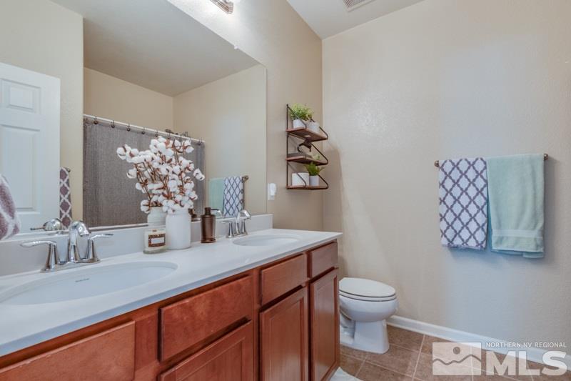 9150 Andraste Way Reno, NV 89506 - Photo 17 of 23 a bathroom with a granite countertop toilet sink and mirror