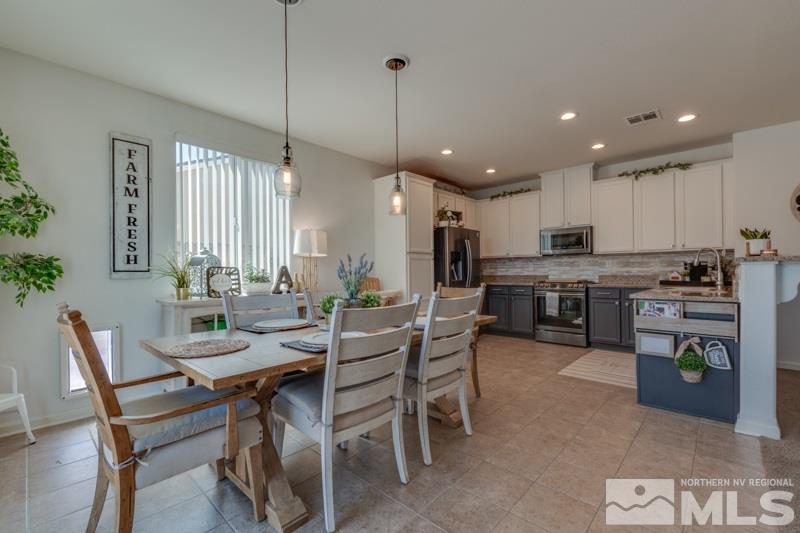 9150 Andraste Way Reno, NV 89506 - Photo 10 of 23 a kitchen with stainless steel appliances kitchen island granite countertop a dining table chairs and white cabinets