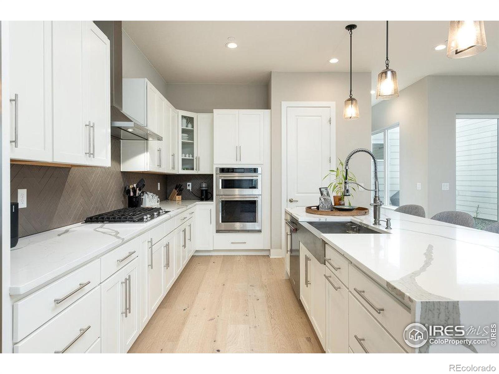 730 Promenade Drive Superior, CO 80027 - Photo 10 of 50 a large kitchen with stainless steel appliances kitchen island granite countertop a sink dishwasher a stove and white cabinets with wooden floor
