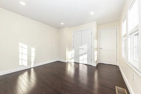 an empty room with wooden floor and windows