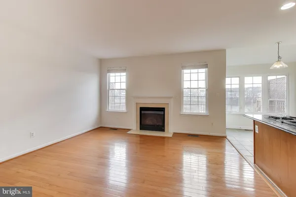 an empty room with wooden floor fireplace and windows