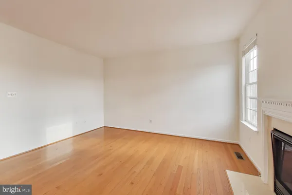 a view of an empty room with wooden floor and a fireplace