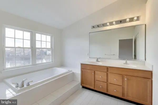 a spacious bathroom with a double vanity sink a large mirror and a bathtub