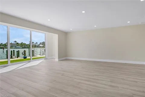 a view of an empty room with a window and a kitchen