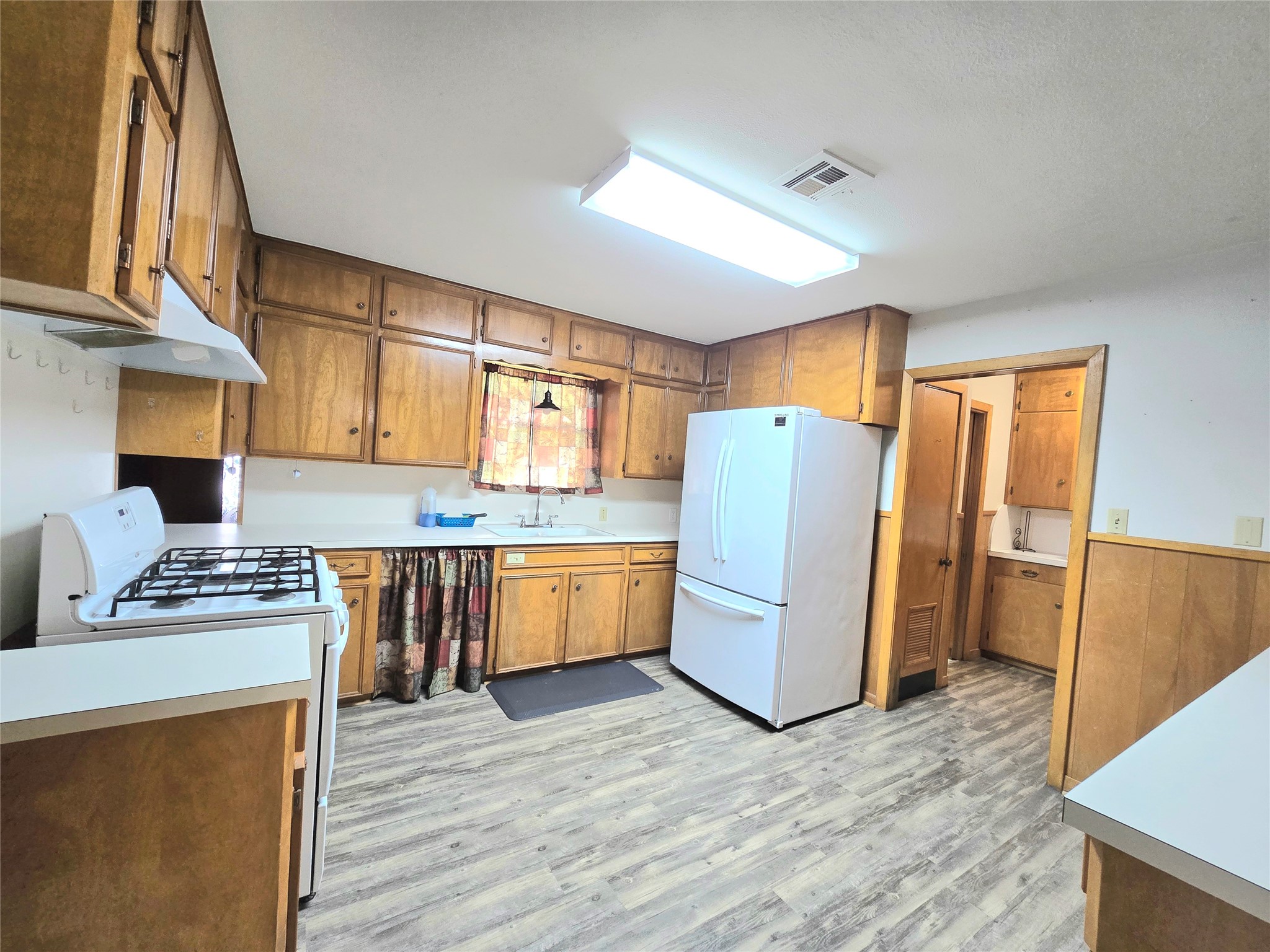 607 South Main Street Dayton, TX 77535 - Photo 9 of 39 a kitchen with stainless steel appliances granite countertop a refrigerator a stove top oven a sink and dishwasher with wooden floor