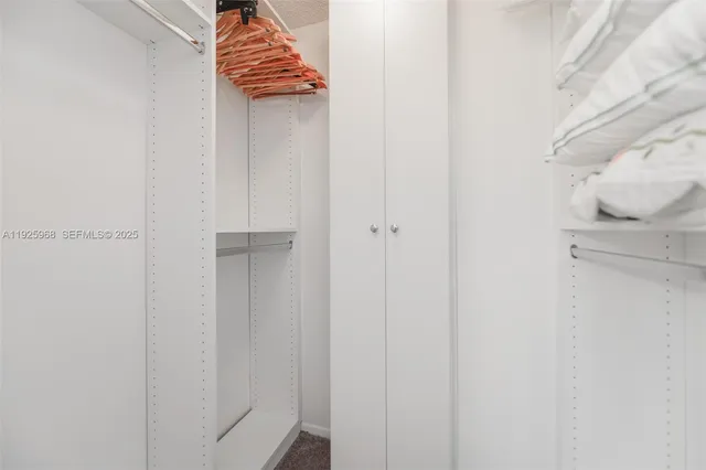a walk in closet with wooden floor
