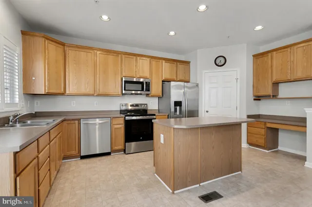 a kitchen with stainless steel appliances granite countertop a stove top oven a sink dishwasher a refrigerator and a microwave