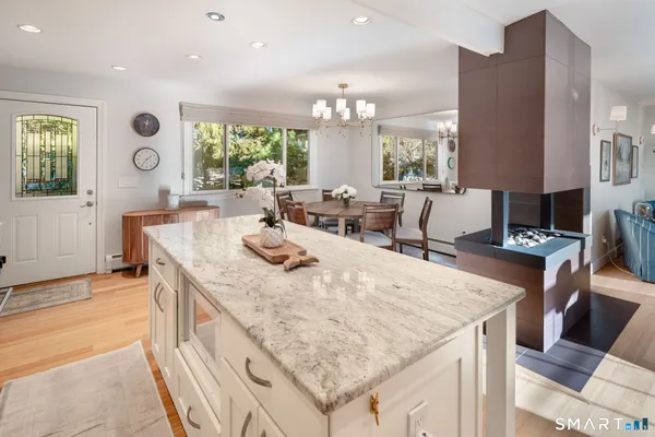 a kitchen with stainless steel appliances granite countertop a stove top oven a sink a dining table and chairs with wooden floor