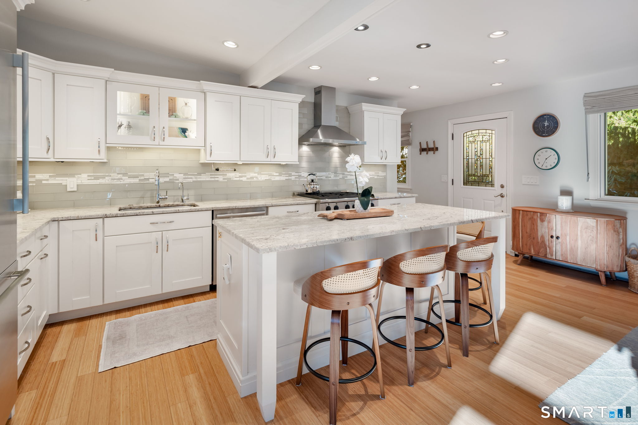 12 Splitrock Road Norwalk, CT 06854 - Photo 6 of 37 a kitchen with stainless steel appliances granite countertop a stove top oven a sink a dining table and chairs with wooden floor