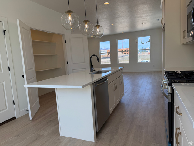 10995 South Freestone Road, Unit 109 South Jordan, UT 84009 - Photo 10 of 20 Kitchen with stainless steel appliances, decorative light fixtures, an island with sink, light wood-type flooring, and white cabinetry
