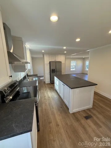 a large kitchen with stainless steel appliances a large counter top and a wooden floors