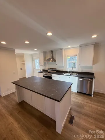 a kitchen with kitchen island stainless steel appliances a sink a stove a counter top space and cabinets